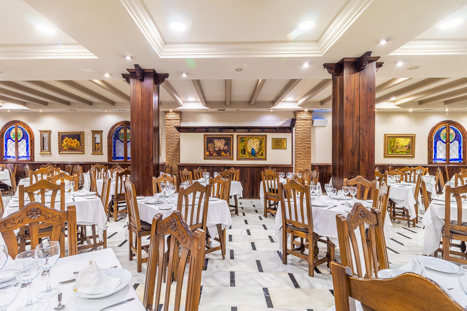 Detalle de la decoración rústica y acogedora del restaurante, con mesas bien dispuestas para eventos especiales.